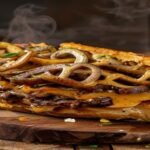Vegan Philly cheesesteak with portobello mushrooms, peppers, onions, and melty dairy-free cheese on a toasted roll (118 chars)